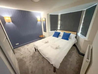 a bedroom with a large white bed with blue pillows at 4 Bed Home In Central Maldon in Maldon