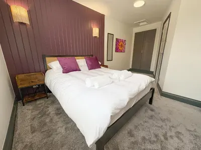 a bedroom with a large white bed with purple pillows at 4 Bed Home In Central Maldon in Maldon