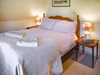 a bedroom with a large bed with white sheets and pillows at Green Farm Cottage in Redgrave