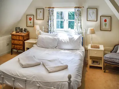 a bedroom with a bed with white sheets and a window at Green Farm Cottage in Redgrave