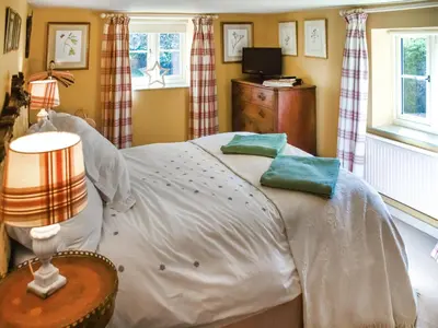 a bedroom with a bed with white sheets and green pillows at Green Farm Cottage in Redgrave