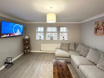 a living room with a couch and a flat screen tv at Apartment I Sleeps 4 I Wi-Fi I Parking I Rail Links I Newmarket in Newmarket