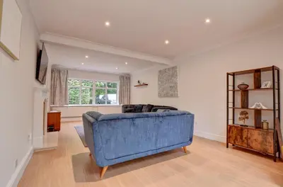 a living room with a blue couch and a mirror at Spacious 4 bedroom house in Bishop's Stortford in Thorley