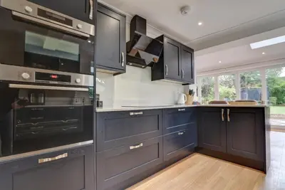 a kitchen with navy blue cabinets and black appliances at Spacious 4 bedroom house in Bishop's Stortford in Thorley