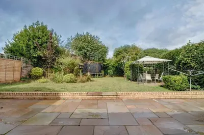 a garden with a patio and an umbrella at Spacious 4 bedroom house in Bishop's Stortford in Thorley