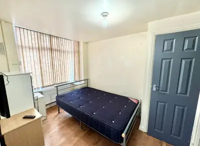 a bedroom with a bed and a tv and a door at Karan Lodge in Mildenhall