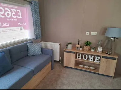 a living room with a blue couch and a table at Karan Lodge in Mildenhall
