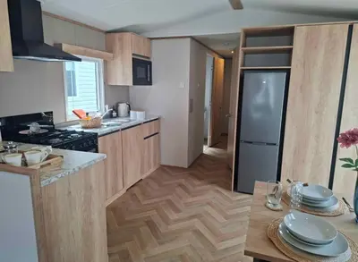 a kitchen with wooden cabinets and a table with plates at Karan Lodge in Mildenhall