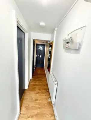 a hallway with white walls and a wooden floor at Karan Lodge in Mildenhall