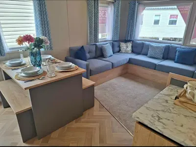 a living room with a blue couch and a table at Karan Lodge in Mildenhall