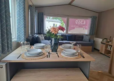 a dining room table with plates and glasses and flowers at Karan Lodge in Mildenhall