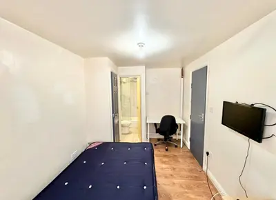 a bedroom with a bed and a tv and a desk at Karan Lodge in Mildenhall