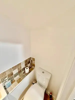 a bathroom with a toilet and a tiled wall at Beautiful Modern 2 Bed house combined with a vintage feel near Central Cambridge Sleeps 4 in Cambridge