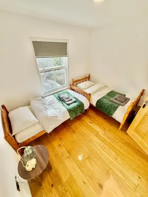 two beds in a room with a window and a table at Beautiful Modern 2 Bed house combined with a vintage feel near Central Cambridge Sleeps 4 in Cambridge