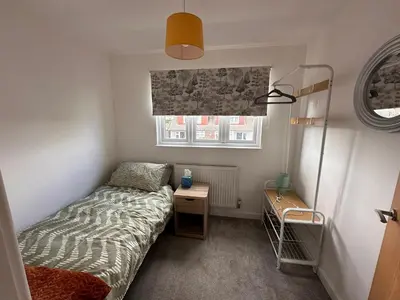 a small bedroom with a bed and a window at The Larks Spacious 3BR Essex in Vange