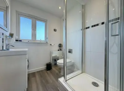 a white bathroom with a shower and a toilet at The Larks Spacious 3BR Essex in Vange