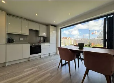 a kitchen with a table and chairs and a large window at The Larks Spacious 3BR Essex in Vange