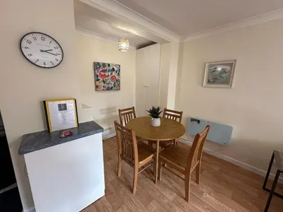 a dining room with a table and a clock on the wall at Ely Stays Flat 2 in Ely