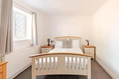 a white bedroom with a bed and a window at Spacious Riverside View Bungalow in Chelmsford
