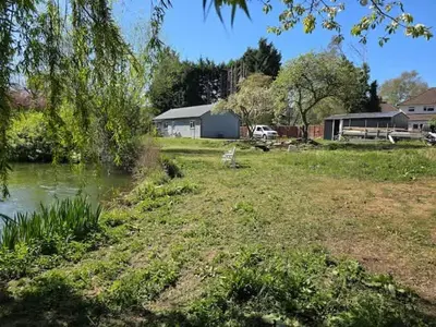 a yard with a pond and a house and trees at Spacious Riverside View Bungalow in Chelmsford