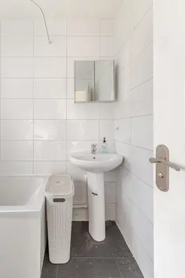 a white bathroom with a sink and a mirror at Spacious Riverside View Bungalow in Chelmsford