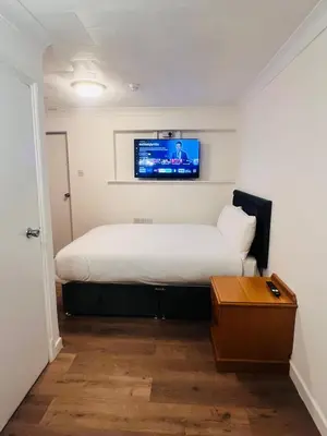 a bedroom with a bed with a tv on the wall at Rivenhall Garden Hotel in Rivenhall