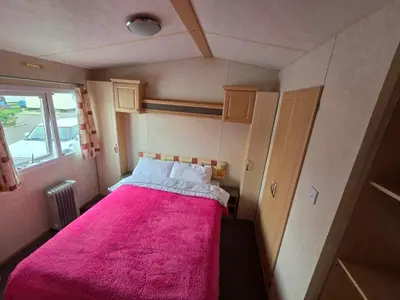 a small room with a pink bed in a trailer at St Osyth, Clacton-on-sea, Cozy Beach side Caravan, Wifi, Tea and Coffee, Parking included in Saint Osyth