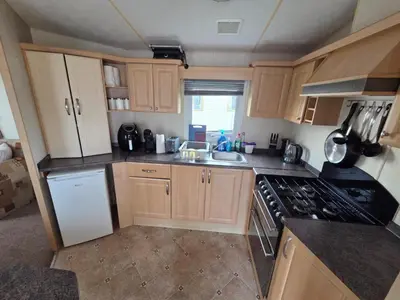 a small kitchen with a stove and a sink at St Osyth, Clacton-on-sea, Cozy Beach side Caravan, Wifi, Tea and Coffee, Parking included in Saint Osyth