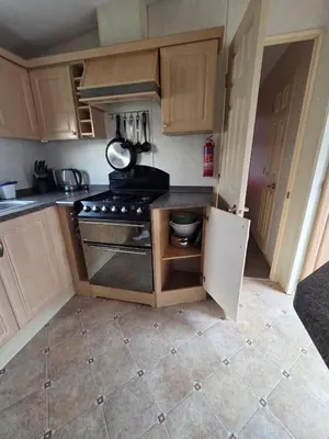 a kitchen with wooden cabinets and a stove top oven at St Osyth, Clacton-on-sea, Cozy Beach side Caravan, Wifi, Tea and Coffee, Parking included in Saint Osyth