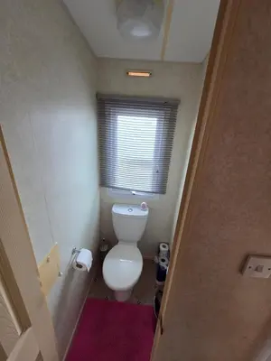 a small bathroom with a toilet and a window at St Osyth, Clacton-on-sea, Cozy Beach side Caravan, Wifi, Tea and Coffee, Parking included in Saint Osyth