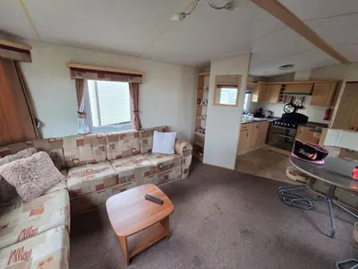 a living room with a couch and a table at St Osyth, Clacton-on-sea, Cozy Beach side Caravan, Wifi, Tea and Coffee, Parking included in Saint Osyth