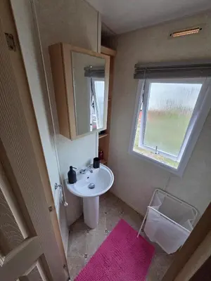 a small bathroom with a sink and a window at St Osyth, Clacton-on-sea, Cozy Beach side Caravan, Wifi, Tea and Coffee, Parking included in Saint Osyth