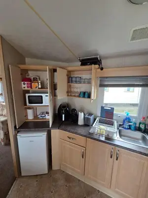 a small kitchen with a sink and a refrigerator at St Osyth, Clacton-on-sea, Cozy Beach side Caravan, Wifi, Tea and Coffee, Parking included in Saint Osyth
