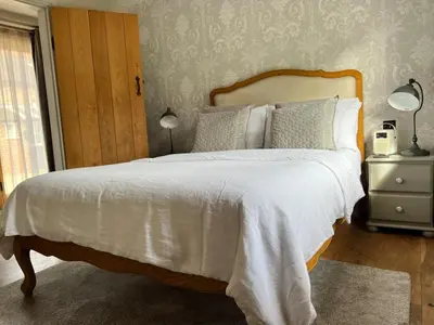 a bedroom with a large bed with a white bedspread at Cosy Barn Conversion - peaceful, private double room in Shenfield