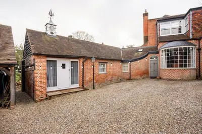 a brick house with a garage and a driveway at Cosy Barn Conversion - peaceful, private double room in Shenfield