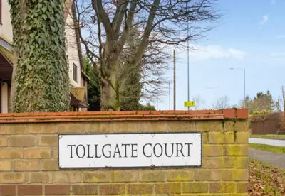 a sign for a tollgate court on a brick wall at K Suites - Tollgate Court in Colchester
