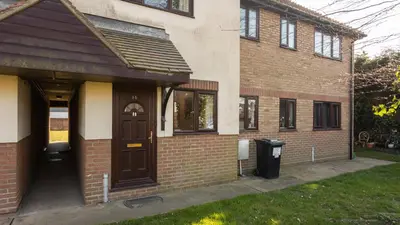 a brick building with a door and a trash can at K Suites - Tollgate Court in Colchester