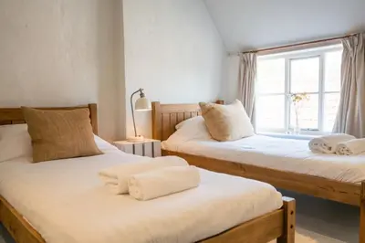 two twin beds in a room with a window at Charming 2BR Cottage in Orford