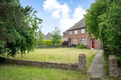 a brick house with a grass yard in front of it at Rosabelle in Wivenhoe