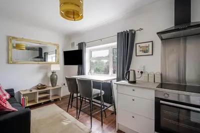 a living room with a kitchen and a table with chairs at Rosabelle in Wivenhoe