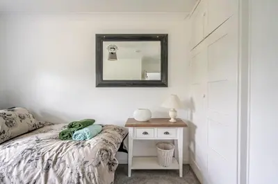 a bedroom with a bed and a mirror and a nightstand at Rosabelle in Wivenhoe
