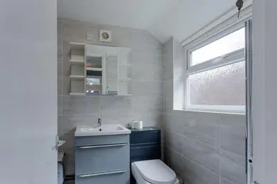 a bathroom with a toilet and a sink and a window at ML Short Stays - 3 bed contractor house near Sizewell C in Leiston