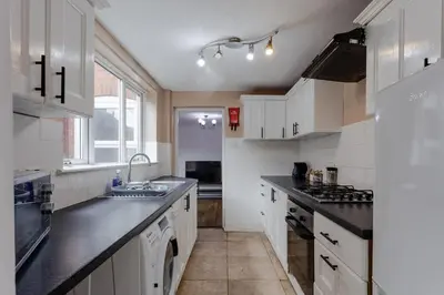 a kitchen with white cabinets and black counter tops at ML Short Stays - 3 bed contractor house near Sizewell C in Leiston