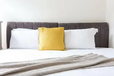 a bed with white pillows and a yellow pillow at Modern 3 Bedroom Home with Parking in Southend in Southend-on-Sea