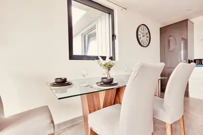 a dining room with a glass table and white chairs at The Opulent Property Project Penthouse Chelmsford 2 Bed 2 Bath Sleeps 6 Free Parking 2 Kings or 4 singles and Double Sofabed Ideal for long stays, corporates, families, Insurance in Chelmsford