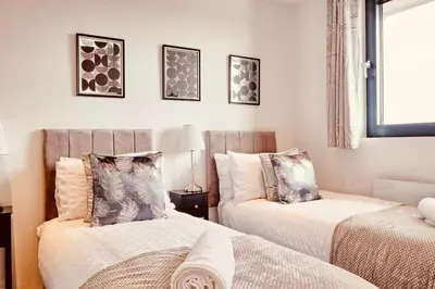 a bedroom with two beds and a window at The Opulent Property Project Penthouse Chelmsford 2 Bed 2 Bath Sleeps 6 Free Parking 2 Kings or 4 singles and Double Sofabed Ideal for long stays, corporates, families, Insurance in Chelmsford