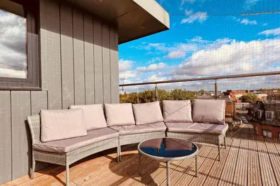 a balcony with a couch and a table at The Opulent Property Project Penthouse Chelmsford 2 Bed 2 Bath Sleeps 6 Free Parking 2 Kings or 4 singles and Double Sofabed Ideal for long stays, corporates, families, Insurance in Chelmsford