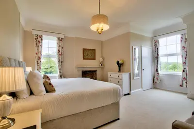 a bedroom with a bed and a fireplace at Holbecks House by Group Retreats in Hadleigh