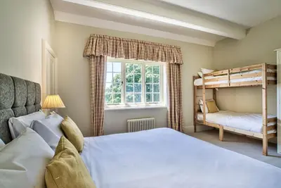 a bedroom with two bunk beds and a window at Holbecks House by Group Retreats in Hadleigh