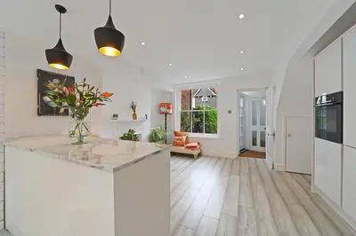 a kitchen with white walls and a counter with a vase of flowers at Beautiful Home at the Heart of Colchester Great for Commuters or Professionals in Colchester